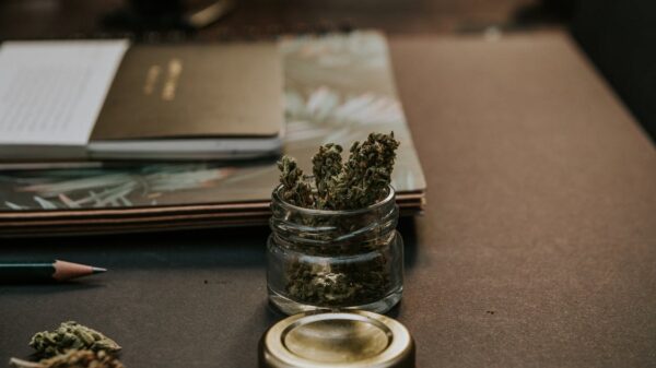 Cannabis is small jar next to a stack of notebooks